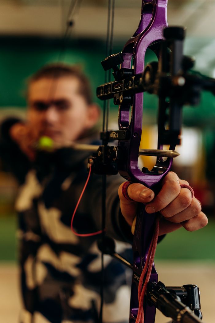 Close-up of a man aiming with a bow and arrow, demonstrating precision and focus in archery.